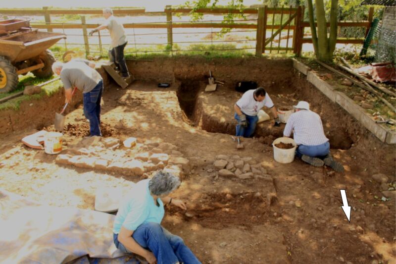 Plate 40. Group excavating in churchyard, T18. The 3rd century enclosure wall can be seen running from above centre left to lower right, top right the 4th century drain continues from section 4 then exits to the left, (west). The Iron Age gully F263, not yet excavated, comes in from section 4 at top left of trench.